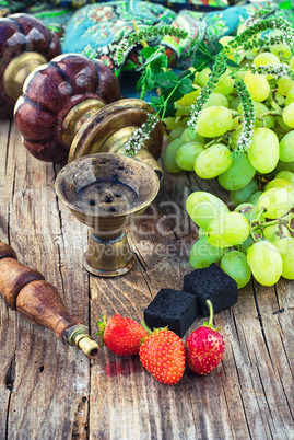 Hookah amid bunches of grapes and strawberries