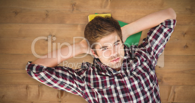 Composite image of hipster with hands behind head lying on hardw