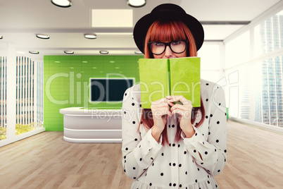 Composite image of hipster woman behind a green book