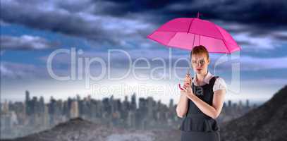 Composite image of pretty redhead businesswoman holding umbrella