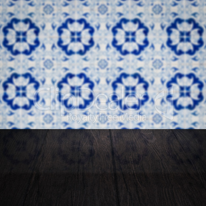 Wood table top and blur vintage ceramic tile pattern wall