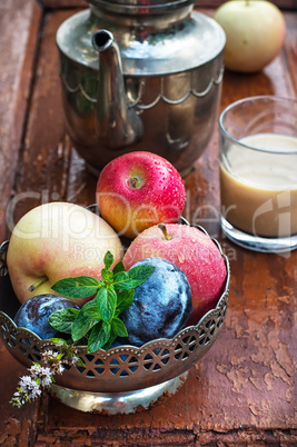 apples and plums in iron vase