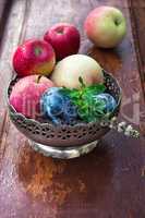 apples and plums in iron vase