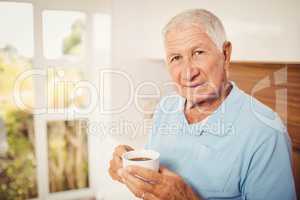 Senior man holding cup and looking at the camera