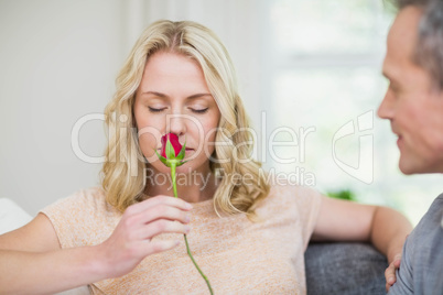 Pretty woman smelling a rose offered by husband