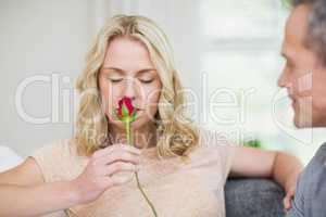 Pretty woman smelling a rose offered by husband
