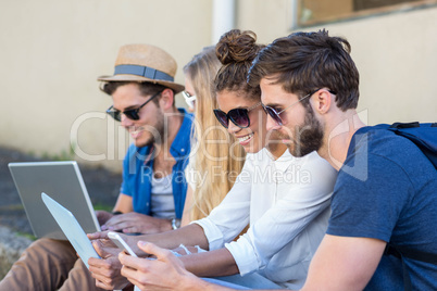 Hip friends sitting on sidewalk