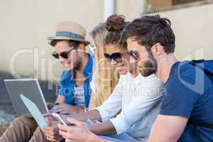 Hip friends sitting on sidewalk