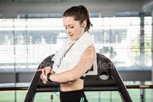 Fit brunette on treadmill using smart watch