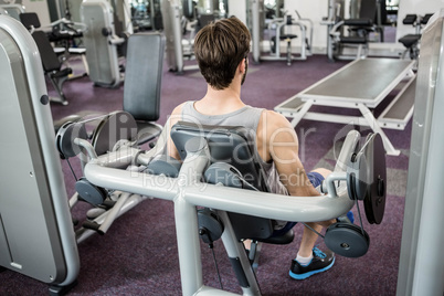 Focused man using weights machine for arms