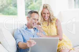 Happy couple using laptop on the sofa