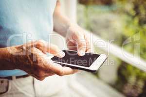 Senior man next to the window using smartphone