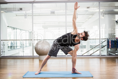 Handsome man doing yoga on mat