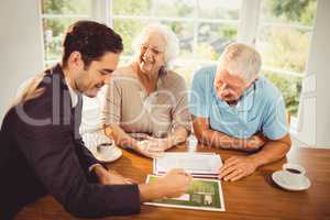 Businessman showing sheets to senior couple