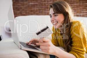 Young woman using her credit card to buy online
