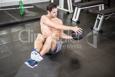 Shirtless man exercising with medicine ball