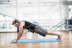 Muscular man doing push up on mat