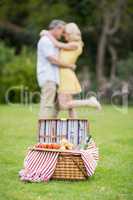 Happy couple hugging next to picnic basket