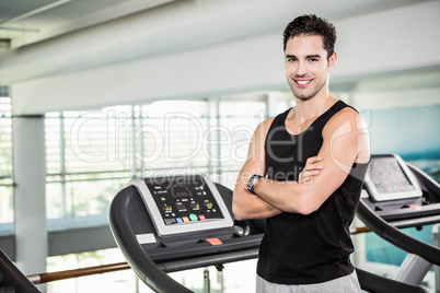 Smiling man on treadmill standing with arms crossed