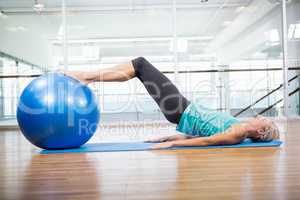 Fit blonde on mat exercising with fitness ball