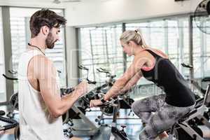 Trainer writing on clipboard and woman using exercise bike