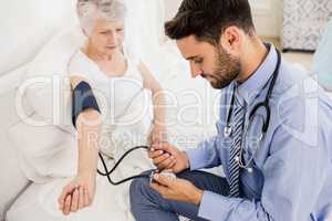 Handsome nurse checking blood pressure of elderly woman