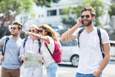 Hip man on phone call and friends checking map