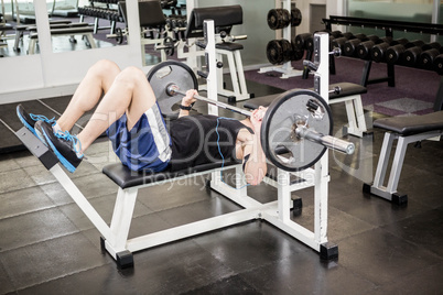 Muscular man lifting barbell on bench