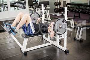 Muscular man lifting barbell on bench
