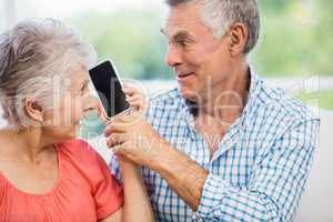 Happy senior couple listening to smartphone