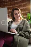 Pretty woman using laptop lying on the couch