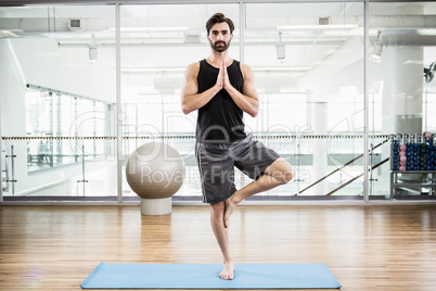 Handsome man doing yoga on mat