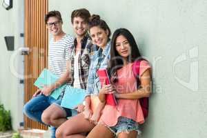 Hip friends leaning against wall and holding notebooks