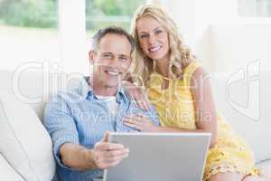 Happy couple using laptop on the sofa