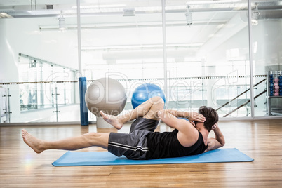 Muscular man doing abdominal on mat