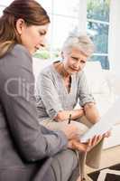 Smiling businesswoman showing documents to senior woman