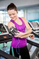 Fit woman using smartphone on treadmill