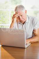 Worried senior man using laptop