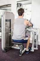 Focused man using weights machine for arms