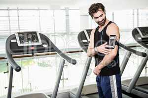 Smiling man standing against treadmills