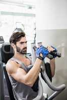 Focused man using weights machine for arms