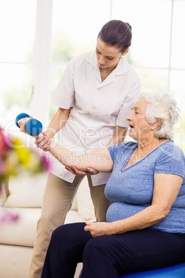 Physiotherapist taking care of sick elderly patient