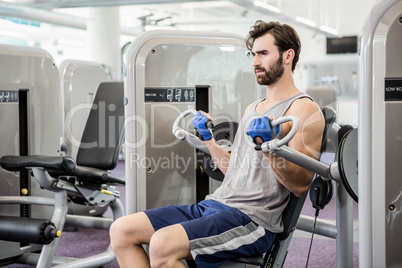 Focused man using weights machine for arms