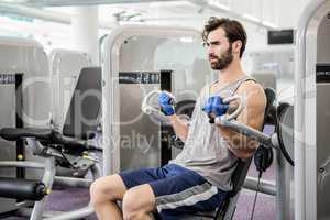 Focused man using weights machine for arms