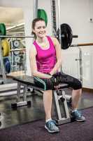 Smiling woman sitting on barbell bench