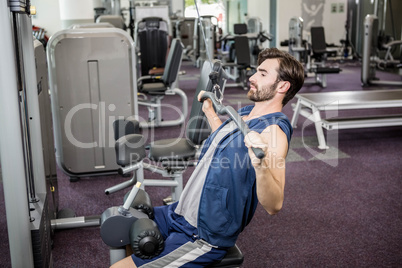 Focused man using weights machine for arms