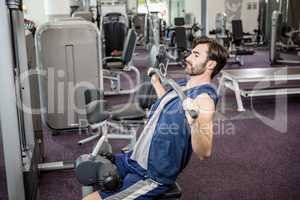 Focused man using weights machine for arms