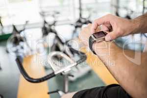 Close up of man using smartwatch on exercise bike