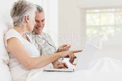 Senior couple using laptop at bed