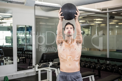 Shirtless man exercising with medicine ball